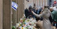 Dinamarqueses colocam flores em frente à sinagoga atacada por um atirador em Copenhague  Foto: Michael Probst / AP