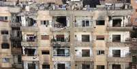 <p>Vista de um prédio danificado por disparos numa área controlada por rebeldes em Homs, na Síria</p>  Foto: Stringer / Reuters