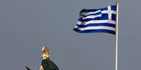 <p>Bandeira da Grécia tremula perto de estátua da deusa Atena, no centro de Atenas</p>  Foto: Yannis Behrakis / Reuters