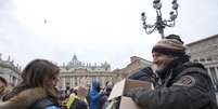Mauro Casubolo, um sem-teto de Roma, entrega um Evangelho de bolso a uma fiel na Praça de São Pedro, após a oração do Angelus conduzida pelo papa Francisco  Foto: Alessandra Tarantino / AP