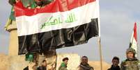 <p>Soldado iraquiano ergue símbolo de vitória próximo à bandeira nacional em Tikrit, Iraque</p>  Foto: EFE en español