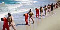 Homens vestidos com roupas laranja são levados para uma praia para serem executados por membros do Estado Islâmico  Foto: Militant Video / AP