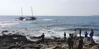 Agentes da guarda costeira grega e locais observam um barco naufragado com imigrantes que tentam chegar à Grécia, perto da ilha de Rodes, nesta segunda-feira. 20/04/2015  Foto: Michalis Loizos / Reuters