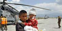 Homem segura uma criança, ferida no terremoto de sábado, depois que soldados indianos os levaram de Trishuli Bazar ao aeroporto em Katmandu, no Nepal, nesta segunda-feira  Foto: Jitendra Prakash / Reuters