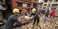 Voluntários ajudam a remover destroços de casa destruída por terremoto em Katmandu  Foto: Wolfgang Rattay / Reuters