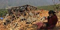 Mulher chora em frente à sua casa destruída (Foto: AP)  Foto: BBC Mundo / Copyright