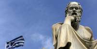 Bandeira da Grécia próxima a estátua do filósofo Sócrates, em Atenas  Foto: Yannis Behrakis / Reuters