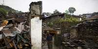V&iacute;tima do terremoto carregando peda&ccedil;os de madeira nos escombros de uma casa no vilarejo de Barpak.   21/05/2015  Foto: Navesh Chitrakar / Reuters