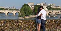 Casais (turistas e parisienses) colocam seus nomes em cadeados de metal e jogam a chave no rio Sena: tradição deve acabar  Foto: The Guardian / Reprodução