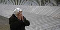 Fadila Efendic, que perdeu o filho e o marido no massacre de Srebrenica, reza ao lado das placas com nomes das vítimas do genocídio no memorial de Potocari, em Srebrenica, na Bósnia, em março. 18/03/2015  Foto: Dado Ruvic / Reuters