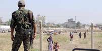 Membro das Unidades de Proteção Popular curdas (YPG) observando moradores, na Síria.  23/06/2015  Foto: Rodi Said / Reuters