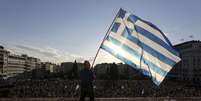 Homem agita a bandeira da Grécia durante manifestação na frente do Parlamento, em Atenas  Foto: Yiannis Liakos / Reuters