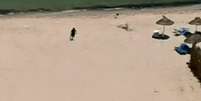 Atirador corre com metralhadora na praia  Foto: BBC News Brasil
