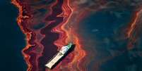 Um barco à deriva em meio ao vazamento de petróleo provocado pelo acidente da plataforma petrolífera Deepwater Horizon, no Golfo do México, em abril de 2010.   Foto: Causa e Efeito/Daniel Beltrá / BBC News Brasil