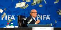 Joseph Blatter foi surpreendido por um comediante antes de uma coletiva em julho; notas de dólar foram jogadas em direção ao então presidente da Fifa  Foto: Philipp Schmidli / Getty Images 
