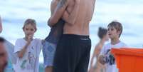 Fernanda Lima beija Rodrigo Hilbert no rosto, enquanto os filhos assistem a cena na praia do Leblon, no Rio de Janeiro, neste domingo (19)  Foto: André Freitas / AgNews