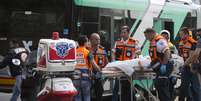 Serviços de emergência retiram um cadáver do ônibus onde pessoas foram atacadas no bairro Armon Hanatziv  Foto: Atef Safadi / EFE