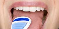 Limpar o fundo da língua com raspadores linguais ajuda a evitar a formação da saburra lingual, uma das principais responsáveis pelo mau hálito  Foto: hightowernrw / Shutterstock
