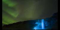 Uma noite clara criou o ambiente para esta foto da aurora boreal sobre a gigantesca cachoeira de Seljalandsfoss, na Islândia.   Foto: Paul Andrew / Observatório Real de Greewich/Divulgação