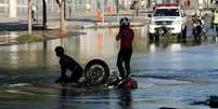 Motociclista e garupa caem em buraco que se abriu após rompimento de uma tubulação da Cedae e que interdita os dois sentidos da Radial Oeste, zona norte do Rio de Janeiro  Foto: José Lucena/Futura Press