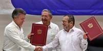 O delegado das Farc em Cuba, Rodrigo Londoño Echeverri (dir.), e o presidente da Colômbia, Juan Manuel Santos (esq.), junto ao presidente de Cuba, Raúl Castro, seguram o acordo de paz entre o governo e a guerrilha durante cerimônia em Havana  Foto: EFE