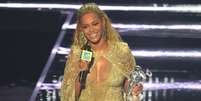 Beyoncé desfilou um macacão longo dourado e brilhoso nos palcos da premiação, onde subiu para receber um dos seus cinco prêmios conquistados da noite. O macacão estava acompanhado de uma capa em renda bordada  Foto: Getty Images, Jason Kempin / PurePeople