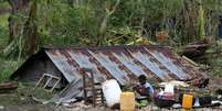 Crian&ccedil;a cozinha ao lado de casa destru&iacute;da pelo furac&atilde;o Matthew no Haiti  Foto: EFE