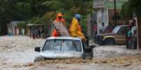 Um grupo de pessoas tenta cruzar uma via alagada in Leogane, no Haiti, após a passagem do Furacão Matthew -  Foto: Agência Brasil