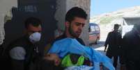 Homem carrega corpo de criança que teria morrido durante bombardeio com armas químicas na Síria  Foto: Reuters