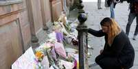 Mulher deposita flores em homenagem às vítimas do atentado após show de Ariana Grande em Manchester.  Foto: Reuters