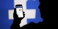Homem acessa Facebook em celular diante de projeção do logo da rede social
14/08/2013 REUTERS/Dado Ruvic/File Photo  Foto: Reuters