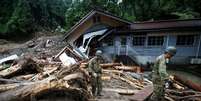 Soldados japoneses caminham em meio a destroços deixados pelas chuvas em Toho. 07/07/2017 REUTERS/Issei Kato  Foto: Reuters