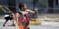 Manifestante atira coquetel molotov contra policiais das tropas do governo venezuelano  Foto: Reuters