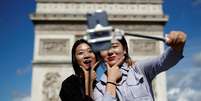 Turistas tiram foto em frente ao Arco do Triunfo, na avenida Champs-Élysées, em Paris   Foto: Reuters