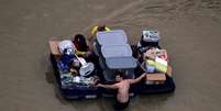 Moradores de Houston transportam seus pertences por ruas alagadas da cidade  Foto: Reuters