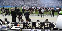 Jogadores do New Orleans Saints sentados durante o hino nacional  Foto: Reuters