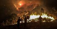 Pessoas olham fogo queimando  Foto: BBC News Brasil