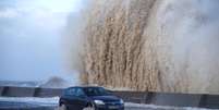 Carro passa por estrada alagada em New Brighton, no Reino Unido  Foto: Reuters