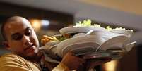 Gar&ccedil;om carrega bandeja de pratos em restaurante de Porto Alegre, Rio Grande do Sul 18/06/2014 REUTERS/Marko Djurica  Foto: Reuters