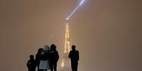 Turistas observam de longe a torre Eiffel cercados pela neve  Foto: Reuters