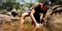 Julio Lobo usa armadilha feita com garrafa plástica para capturar pequenos peixes; ele tem no sobrevivencialismo fonte de renda com produção de conteúdo, loja online e cursos | Foto: Arquivo pessoal  Foto: BBC News Brasil
