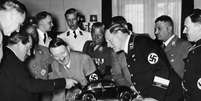 Ferdinand Porsche (esq.) explica a Hitler seu projeto de carro popular "Volkswagen"  Foto:  Hoffmann / Getty Images 