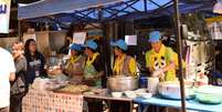 Voluntários e funcionários da cozinha real tailandesa preparam refeições para todos no acampamento da operação de resgate  Foto: BBC News Brasil