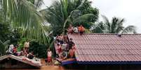 Moradores sobem nos telhados das casas após rompimento de barragem de hidrelétrica no Laos 24/07/2018  Foto: ABC Laos News/Divulgação via Reuters / Reuters