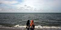 Duas mulheres na praia de Kota Bharu, na Malasia  Foto: Rahman Roslan / Getty Images