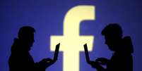Pessoas usam computadores diante de projeção do logo do Facebook em foto ilustativa
28/03/2018 REUTERS/Dado Ruvic/Illustration  Foto: Dado Ruvic/Illustration / Reuters