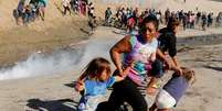 Fam&iacute;lia de Honduras corre para fugir do g&aacute;s lacrimog&ecirc;neo na fronteira do M&eacute;xico com os Estados Unidos em Tijuana 25/11/2018 REUTERS/Kim Kyung-Hoon  Foto: Kim Kyung-Hoon / Reuters