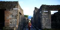 Turista caminha ao longo de uma antiga rua de paralelepípedos romanos em Pompéia, Património Mundial da UNESCO  Foto: Alessandro Bianchi / Reuters