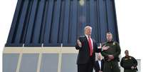 Trump ao lado de um possível protótipo de muro para a fronteira; orçamento da obra causa um impasse no governo americano  Foto: Getty Images / BBC News Brasil