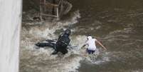 Pedestre ajuda motociclista arrastado pelas &aacute;guas da chuva na Avenida Nove de Julho, no centro da capital paulista  Foto: D&aacute;rio Oliveira / Estad&atilde;o
